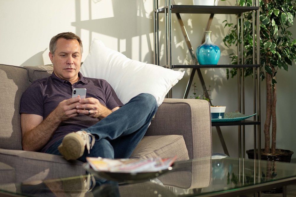 Man sitting on a couch while being using his phone.