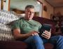 Image of Veteran sitting on a sofa using his tablet.