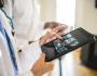 Image of doctor holding a tablet and looking at the screen.